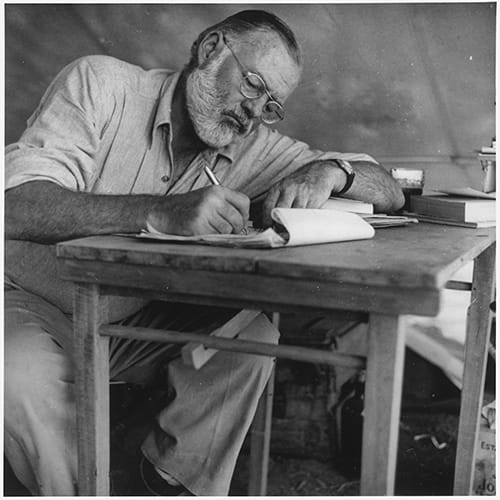 Ernest_Hemingway_Writing_at_Campsite_in_Kenya_-_NARA_-_192655.jpg